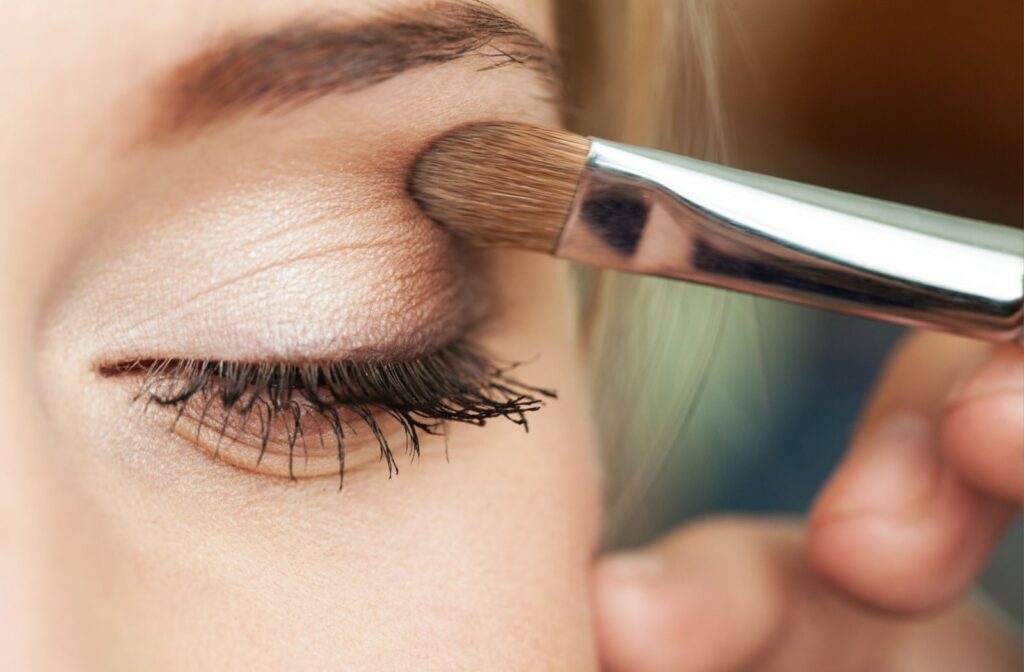 A woman uses a brush to apply eye shadow to her eyelid