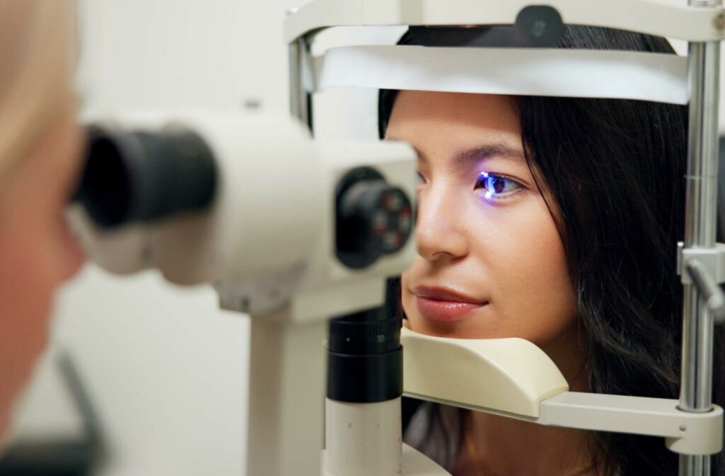 a person on a piece of eye exam equipment getting screened for eye conditions.