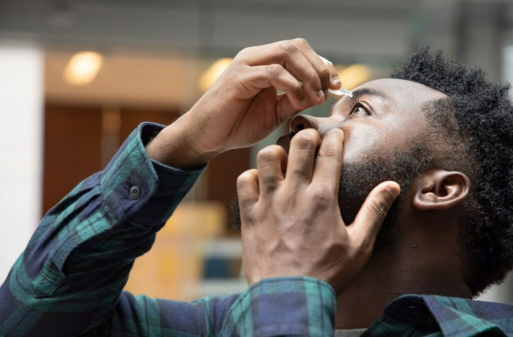 A person using eye drops to relieve eye dryness caused by dry eye syndrome