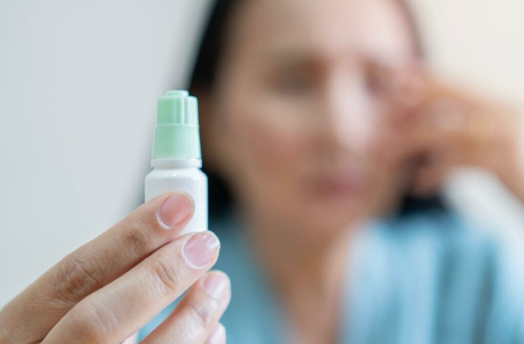 A person holds out a potentially expired eye drop bottle.