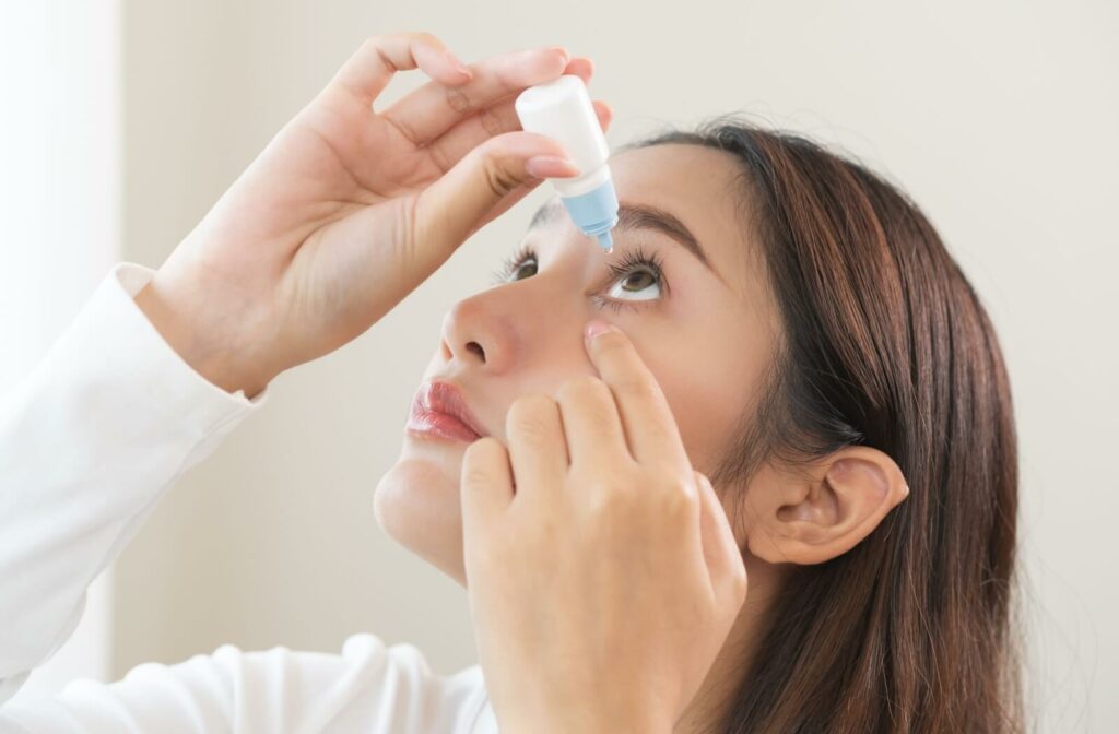 A person tilts their head back to apply eye drops.